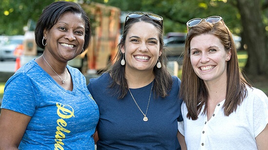 Three women on campus with one wearing a Delaware T-Shirt
