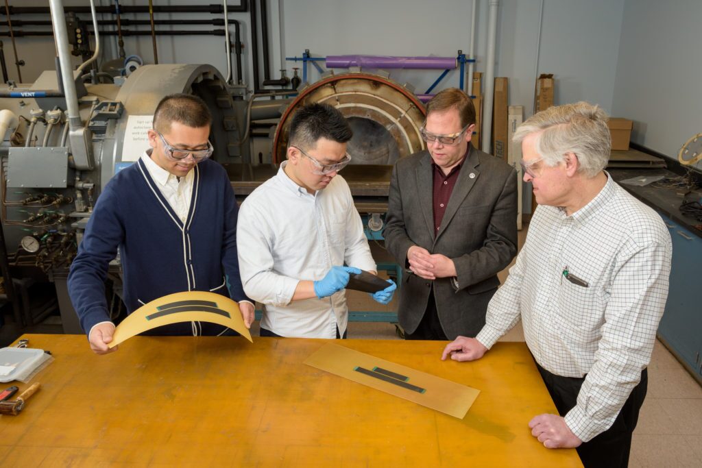 Graduate students Hao Liu and Hongbo Dai with their advisor, assistant professor Erik Thostenson, and affiliated professor / founder of "Geeks4Hire", William B. Johnson. Liu and Dai have worked to develop a carbon nanotube integrated multifunctional composite sensor for in situ structural health monitoring. - (Evan Krape / University of Delaware)