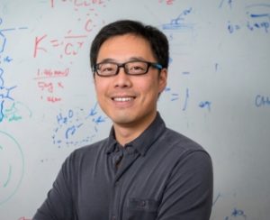 Bingjun Xu is pictured in front of a white board. 