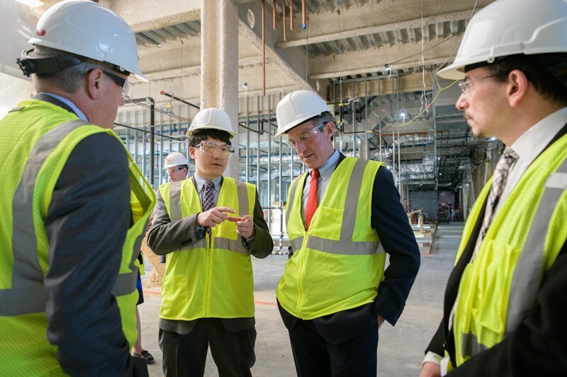 Kelvin Lee, director of the National Institute for Innovation in Manufacturing Biopharmaceuticals (NIIMBL) and Gore Professor of Chemical Engineering at UD, answers questions from Delaware Gov. John Carney during a tour of the Carol Ammon and Marie Pinizzotto M.D. Biopharmaceutical Innovation Center, under construction on UD's STAR Campus. On the far left is Jeff Garland, vice president and University secretary, and on the far right is John Koh, director of the Delaware Biotechnology Institute.
