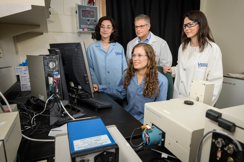 UD Professors Emily Day (right) and Joel Rosenthal (middle, back) have combined efforts to improve existing light-activated cancer treatments. Graduate student Andrea Potocny (seated) and undergraduate Rachel O’Sullivan (left) have helped with the research.