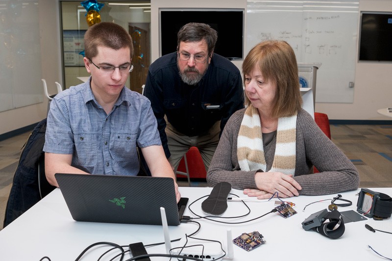 UD junior Theodore Fleck (far left) demonstrates the web interface he helped build to remotely control the device’s vibrating motors and log the data collected by sensors for Prof. Scott Jones and Ingrid Pretzer-Aboff, senior nurse scientist at Virginia Commonwealth University.