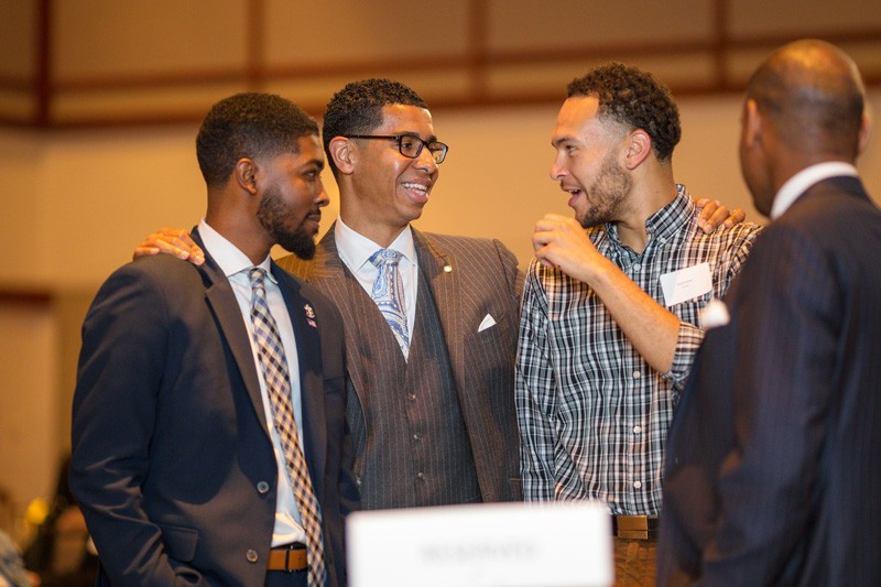  Wali Rushdan II (second from left) speaks with students during the 2019 Students of Distinction dinner. 