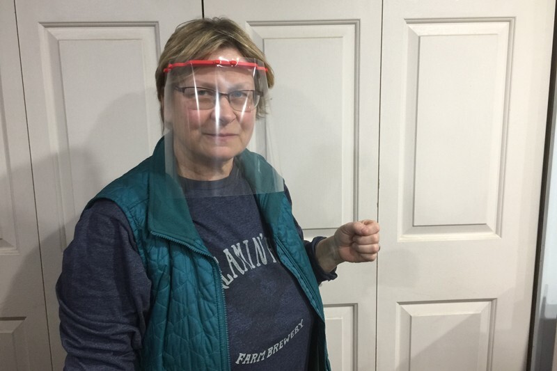 MakerGym technician Donna Svinis models one of the clear plastic face shields she helped design and produce.
