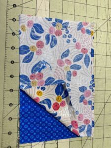 two multi-colored pieces of cloth on a cutting mat.