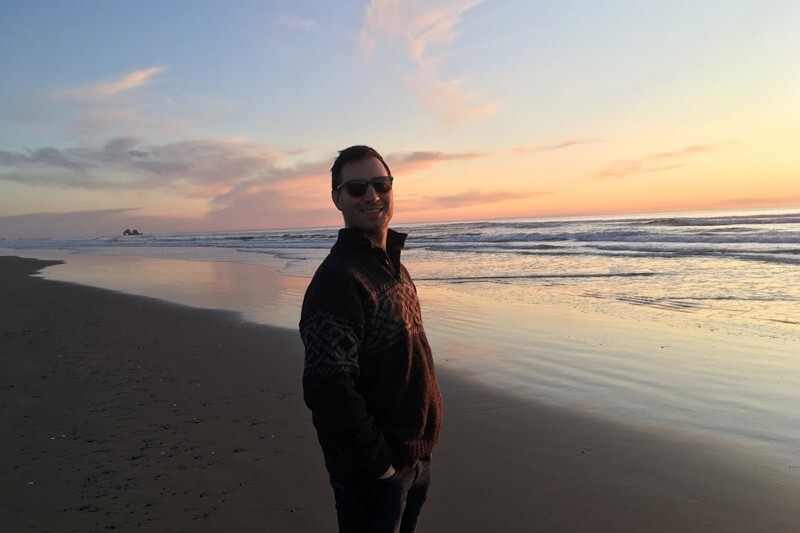 Josh Lansford stands on a beach at sunset.