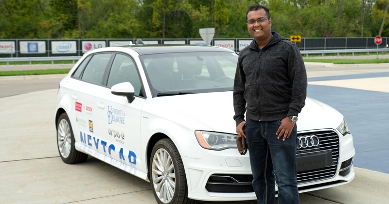 UD doctoral student A M Ishtiaque Mahbub stands in front of a white test vehicle.
