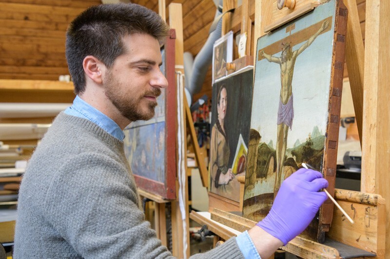 Isaac Messina surface cleans a late 15th-century Italian panel painting in the painting conservation studio at Winterthur.