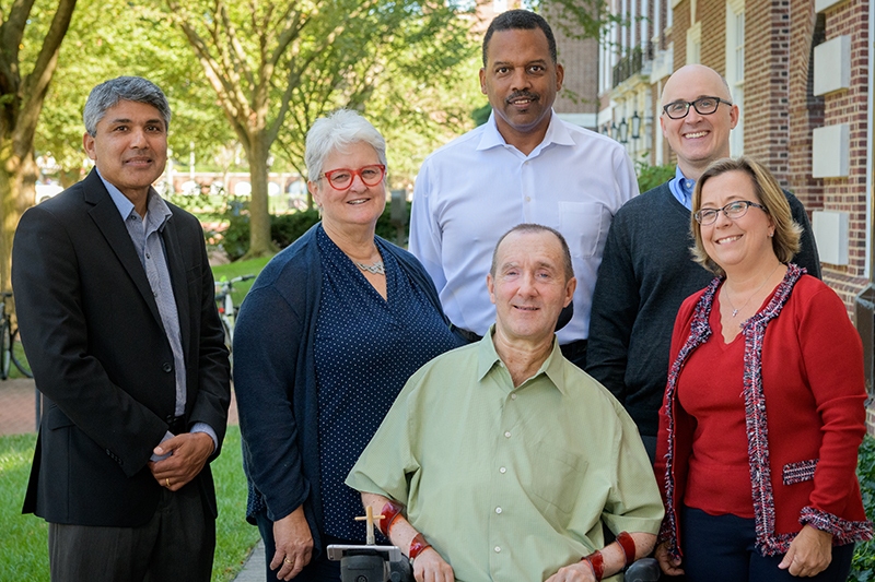 Several faculty members gathered outside a brick building