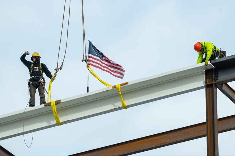 Workers guide the final beam into place on Wednesday, Feb. 10, marking the halfway point of construction on the FinTech Innovation Hub on UD’s STAR Campus.
