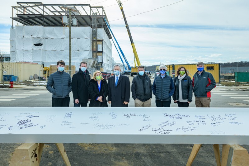 Among those who signed the final beam were (from left): John Weber, a sophomore in the Alfred Lerner College of Business and Economics; Bruce Weber, dean of the Lerner College; Eleni Assanis; Dennis Assanis, president of the University; Matt Parks, vice president of investments, community reinvestment and retail banking with Discover Financial Services and a 2002 UD MBA graduate; Mike Bowman, president of Delaware Technology Park and associate director of UD’s Office of Economic Innovation and Partnerships; Beth Brand, vice president and University secretary; and Charles G. Riordan, vice president of research, scholarship and innovation, and professor of chemistry and biochemistry.