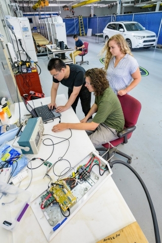 Students in a electric vehicle lab gather around a computer.
