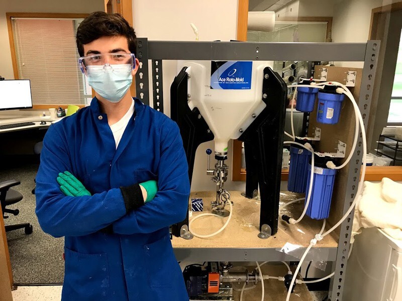 UD senior Colin Post, a chemical engineering major, is standing next to a filtration station he built to efficiently remove micron-scale particulate matter from the polymer material