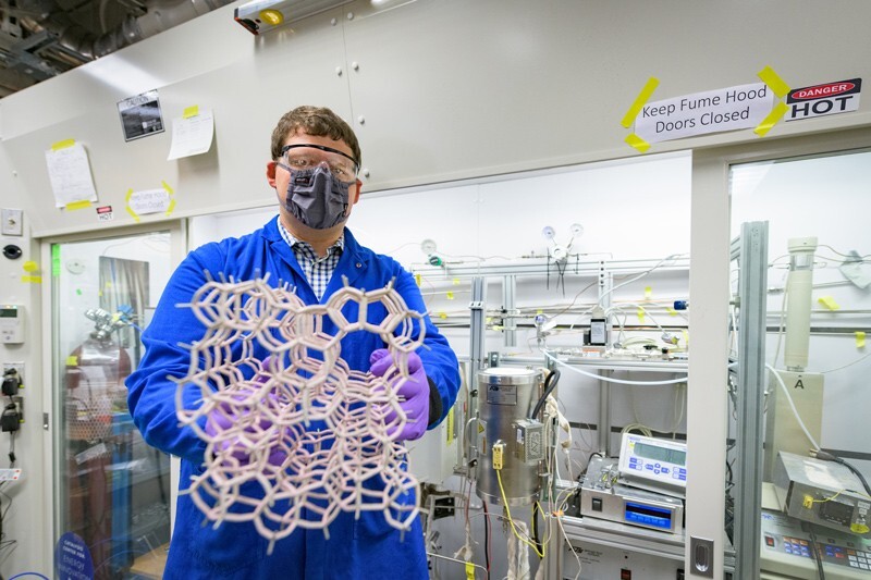 The University of Delaware’s Mark LaFollette, a doctoral student in chemical and biomolecular engineering at UD, displays a large structural model of a zeolite. The honeycomb-like structure allows zeolites to act as a “molecular sieve.”