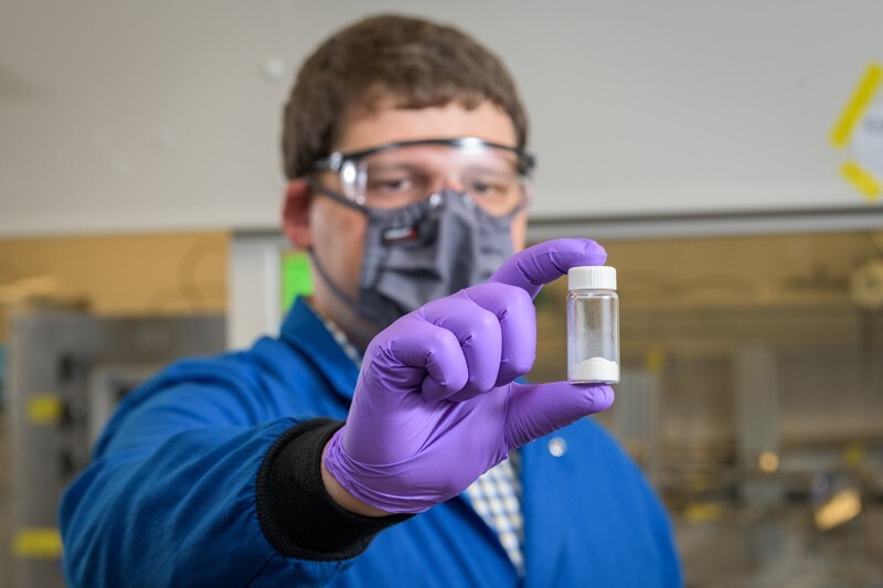 Doctoral student Mark LaFollette works with zeolites in a sample bottle