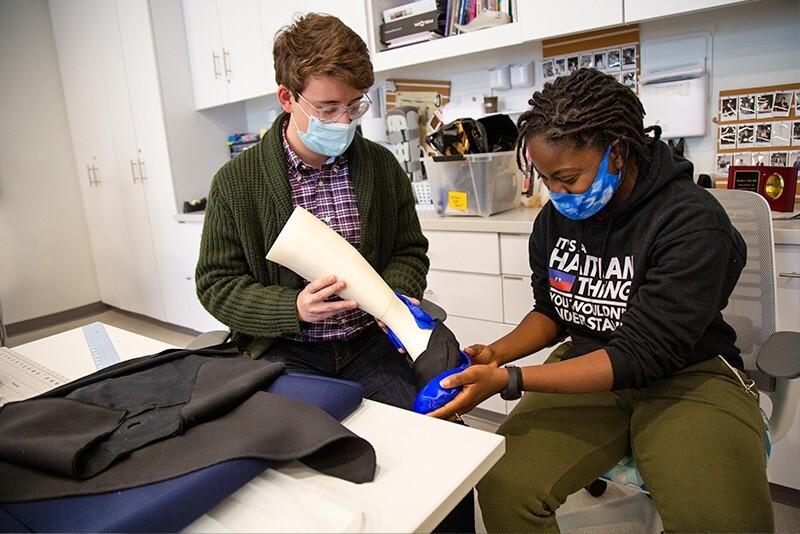 Nathaniel George and Sarah Garcon assemble a walking boot design made of cloth and plastic.