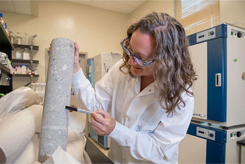 Julie Maresca holds one of the concrete cylinders.