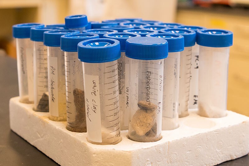 Blue-topped, plastic test tubes contain bits of concrete for testing.