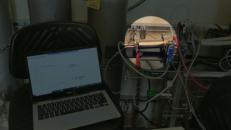 This picture shows the electrochemical system developed by the Yan group. Inside the highlighted cylindrical metal housing shown is the research team’s novel spiral wound module. As hydrogen is fed to the device, it powers the carbon dioxide removal process. Computer software on the laptop plots the carbon dioxide concentration in the air after passing through the module.