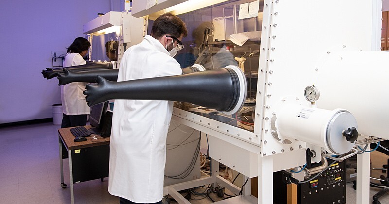Researchers in a lab with chemical hoods known as air-free glove boxes.