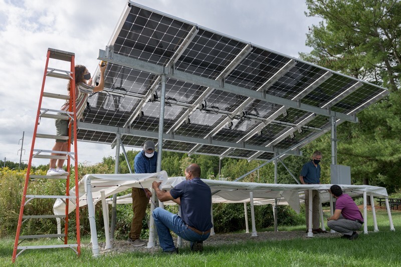 People assembling a solar array. In this image are (left to right): undergraduate Ryan Purnell (on the ladder), Kunal Vohra, a recent UD graduate student, IEC research technician Shannon Field, Professor Steven Hegedus, leader of the project, and doctoral student Sergio Sepúlveda.
