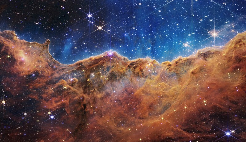 Captured in infrared light by NASA’s new James Webb Space Telescope, this image reveals for the first time previously invisible areas of star birth. According to NASA, this image shows a landscape of “mountains” and “valleys” speckled with glittering stars, but is actually the edge of a nearby, young, star-forming region called NGC 3324 in the Carina Nebula.