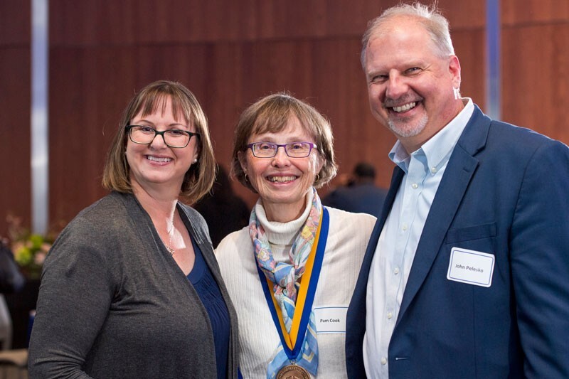 At the May event, Pam Cook (center) is congratulated by Michelle Cirillo, associate professor of mathematical sciences, and John Pelesko, dean of the College of Arts and Sciences.