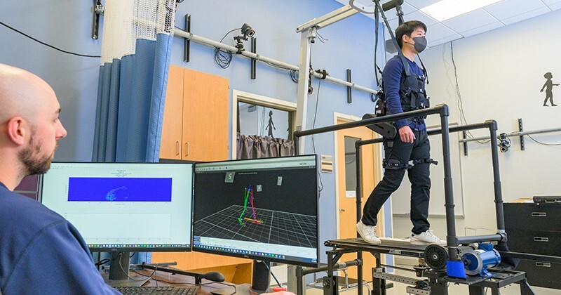 Doctoral student GilHwan Kim (right) demonstrates the robotic device and adaptive treadmill set-up, a unique approach that more closely mimics how patients will respond in real-world settings.