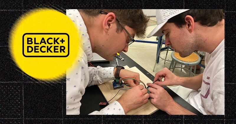 Two students assemble an electronic device. An inset of the Black and Decker logo.