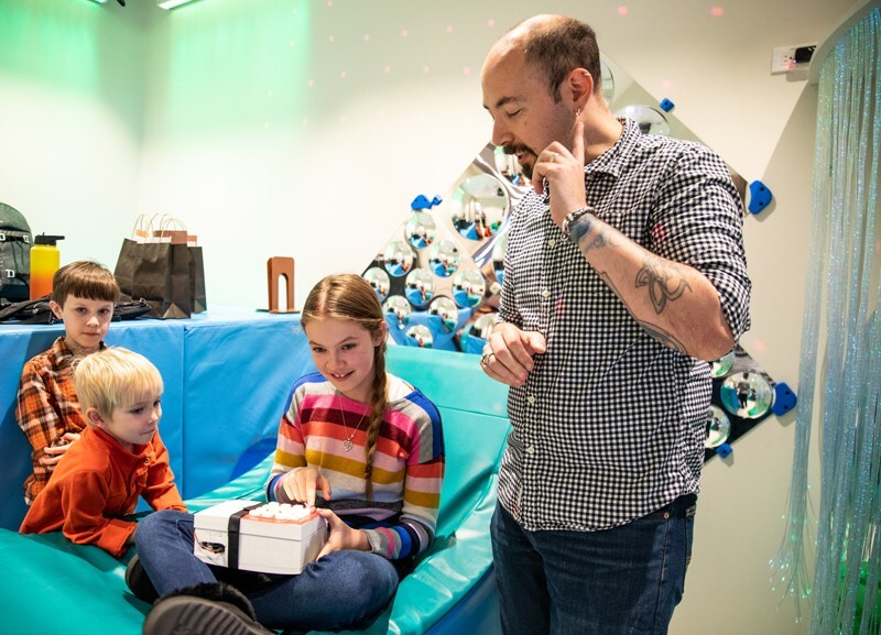 Matthew Mauriello (right), assistant professor of computer and information sciences, helped to design, build and deploy the technology used in the music listening device for children with autism. He is pictured showing children how to use the device inside the Route 9 Library and Innovation Center.
