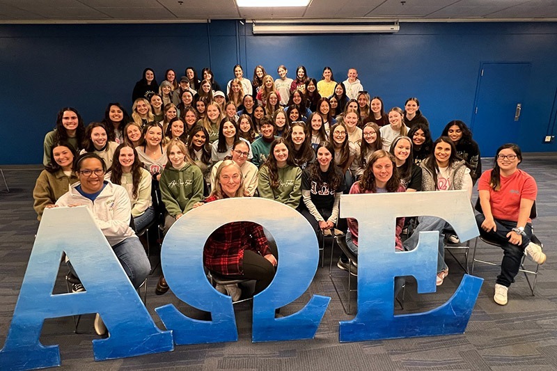 All attendees of the 20th anniversary event pose with the A.O.E. letters.