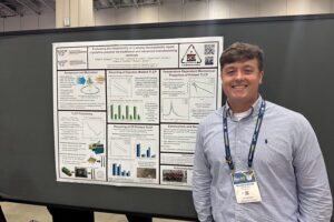 Will Quintana poses next to his scientific poster.