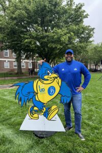 Charles Johnson-Bey poses with a cut out of the YouDee mascot.