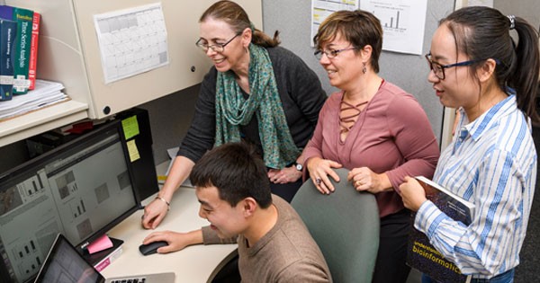 Pengyuan Li (seated), then left-to-right, Hagit Shatkay, Cecilia Arighi and Xiangying Jiang review biomedical images.