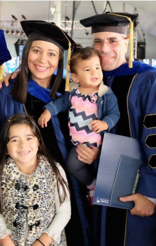 Parents in graduation robes holding children