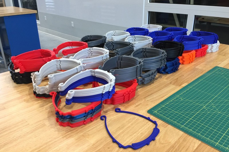 Multi-colored stacks of 3D printed plastic frames to hold face shields.